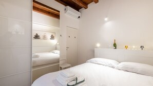 A hotel room with a bed, a small bedside table, a mirror, and a wall-mounted air conditioning unit. - BnButler - Black Mountain, 62 (Milano)