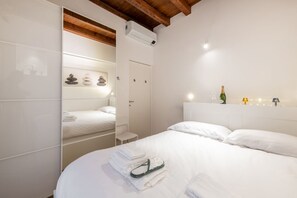Une chambre d’hôtel avec un lit, une petite table de chevet, un miroir et un appareil de climatisation fixé au mur.