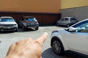 Un parcheggio con diverse auto, tra cui un SUV bianco e una utilitaria argentata.