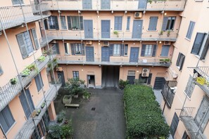 A multi-story building with balconies, a courtyard, and potted plants.
