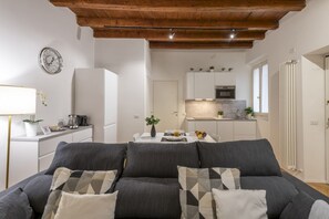 A modern living room with a sofa, a dining table, and a kitchen in the background. - BnButler - Black Mountain, 62 (Milano)
