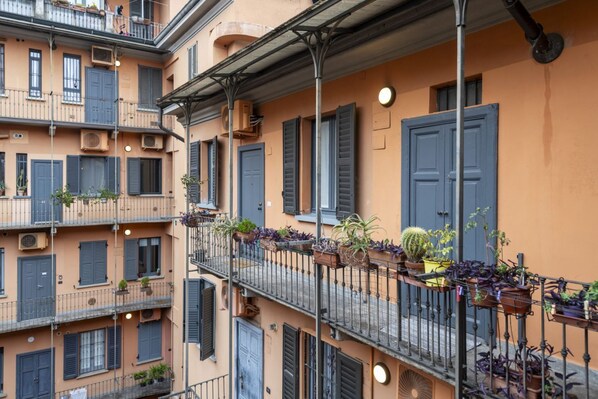 A multi-story building with balconies, air conditioning units, and potted plants. - BnButler - Black Mountain, 62 (Milano)