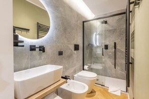 A modern bathroom with a bathtub, bidet, and glass-enclosed shower.