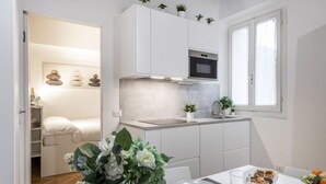 A compact kitchen with white cabinets, a built-in oven, and a window. - BnButler - Black Mountain, 62 (Milano)