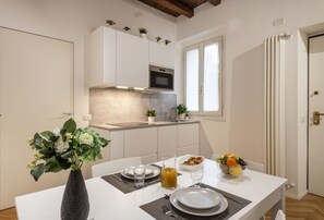 A compact kitchen with white cabinets, a built-in oven, and a window above the sink.