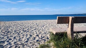 Uma praia arenosa com um banco de pedra.