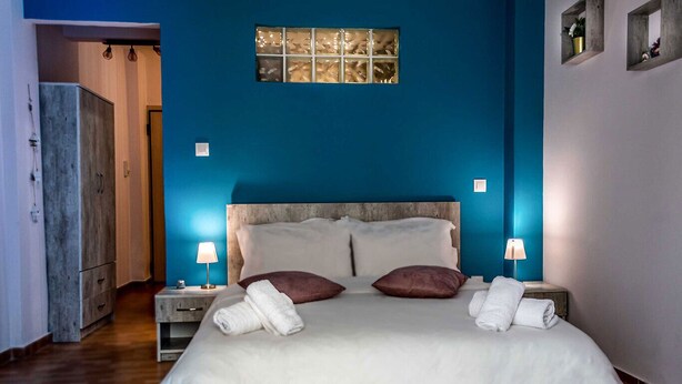 Une chambre à coucher avec un grand lit, deux lampes de chevet, une tête de lit en bois et une fenêtre avec des stores.