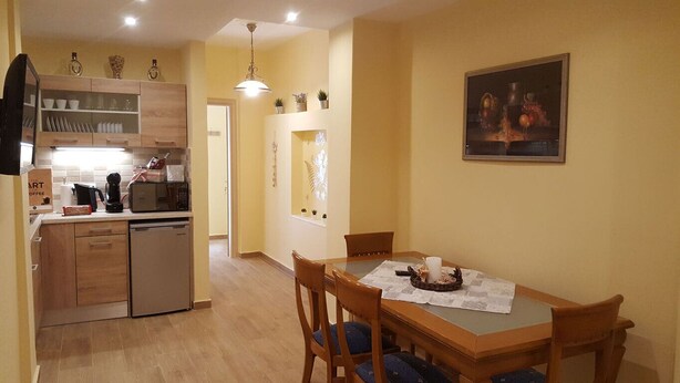 A compact kitchen with a dining area, wooden cabinets, a microwave, and a dining table with chairs. - Zoe's Studio Superior (Athens)