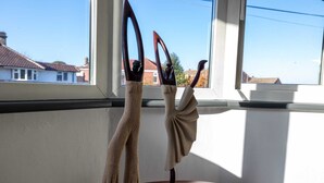 Deux sculptures dans une pièce donnant sur des maisons par une fenêtre.