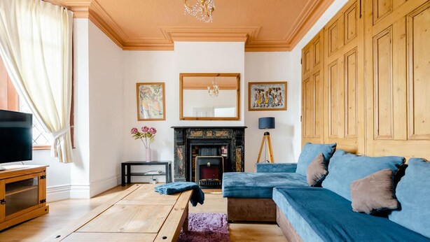 A living room with a wooden coffee table, a blue sofa, a fireplace, and a television. - Stunning 2-bed Apartment in Dartford (Dartford)
