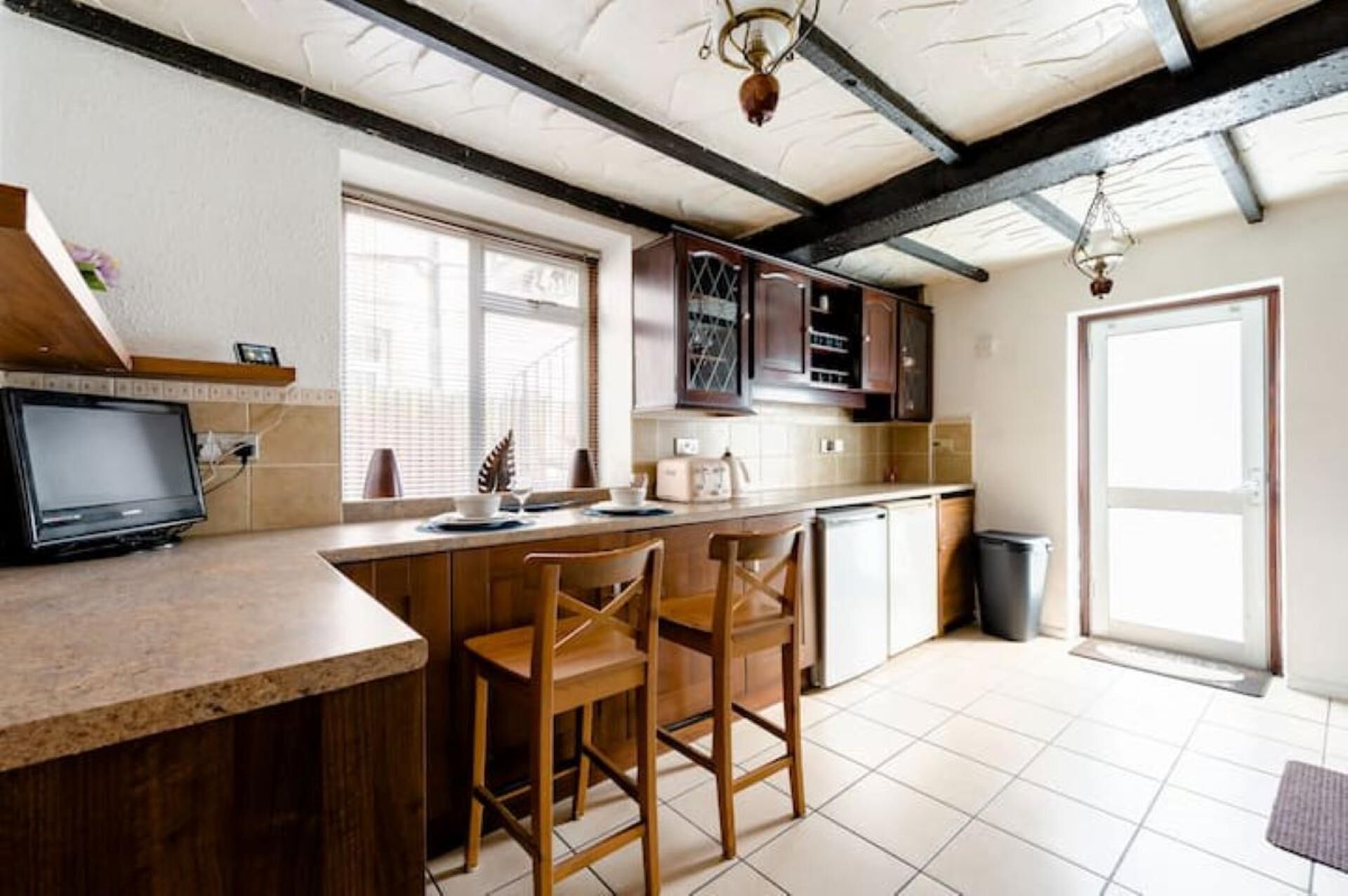 Une cuisine avec des meubles de rangement en bois, un four encastré, un évier et une fenêtre.