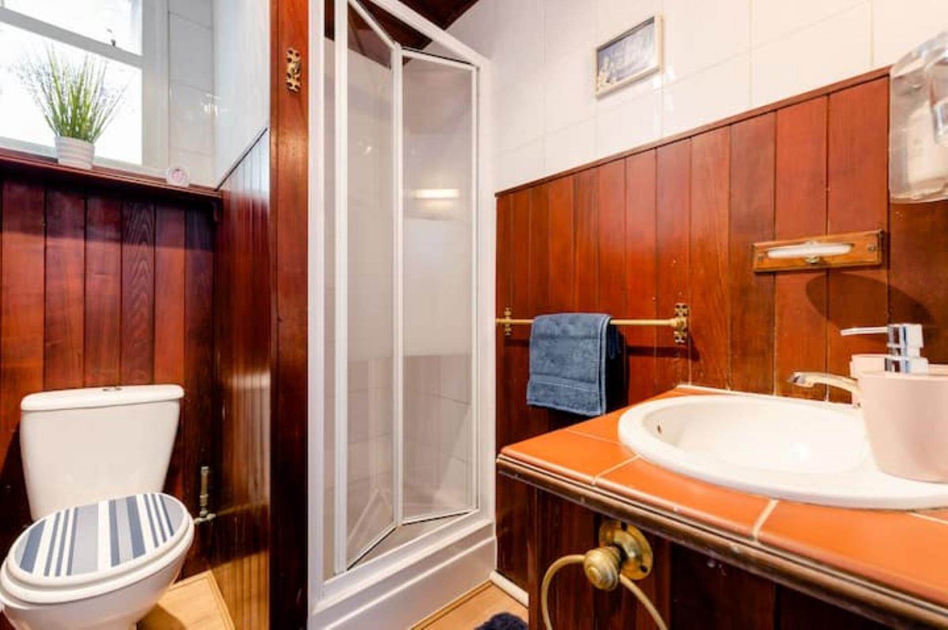 A bathroom with a wooden vanity, a white sink, and a shower enclosure.