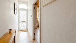 A hallway with a wooden bench, a door with a glass panel, and a framed picture on the wall. - Stunning 2-bed Apartment in Dartford (Dartford)