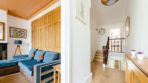 A room with a blue sofa, a wooden cabinet, and a lamp. - Stunning 2-bed Apartment in Dartford (Dartford)