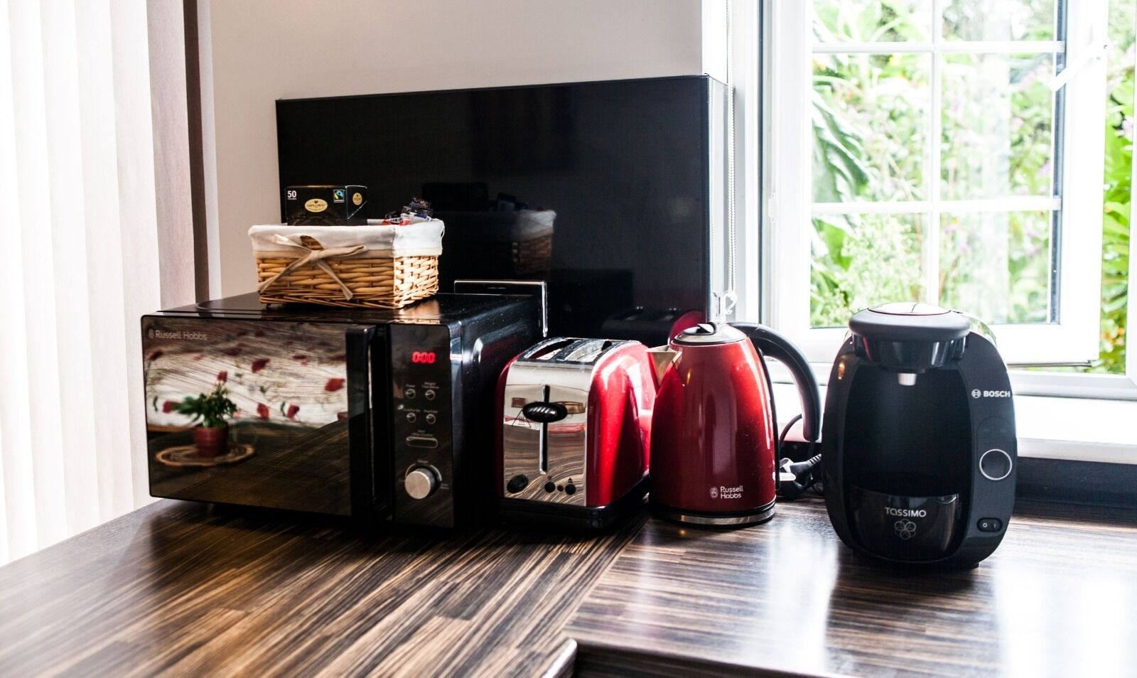 Een keuken met een broodrooster, waterkoker en koffiezetapparaat op een houten aanrecht.