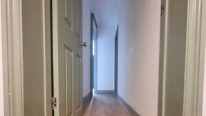 A narrow hallway with wooden flooring and green-painted doors. - Elegant 4-bed House in Dartford (Dartford)
