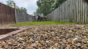 A gravel pathway leading to a wooden fence with a bench and a table in the background. - Gorgeous 4-bedroom House in Orpington (Orpington)
