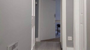 A narrow hallway with white walls and a door leading to another room. - Gorgeous 4-bedroom House in Orpington (Orpington)