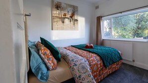 A bedroom with a bed, a window, a radiator, and a painting on the wall. - Immaculate 2-bed Apartment in Dartford (Dartford)