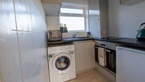 A compact kitchen with a built-in washer, oven, and a window above the sink. - Immaculate 2-bed Apartment in Dartford (Dartford)