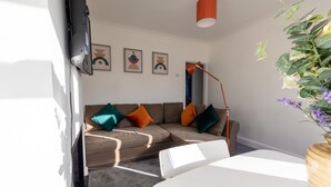 A modern living room with a sectional sofa, a white table, and a floor lamp. - Immaculate 2-bed Apartment in Dartford (Dartford)