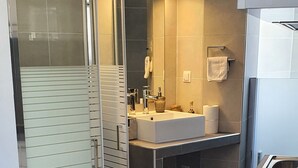 A modern bathroom with a glass shower enclosure, a sink, and a toilet.