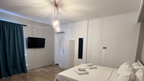 A bedroom with a bed, a TV, a wardrobe, and a desk with a lamp. - Nikis Penthouse 4th Floor (Athens)
