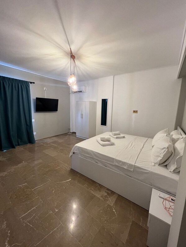 A bedroom with a bed, a TV, a wardrobe, and a desk with a lamp. - Nikis Penthouse 4th Floor (Athens)