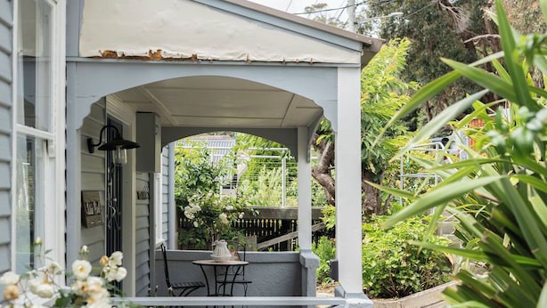 A covered porch with a table and chairs, surrounded by greenery and a fence. - View Point: Ocean Views & Near CBD (Burnie)