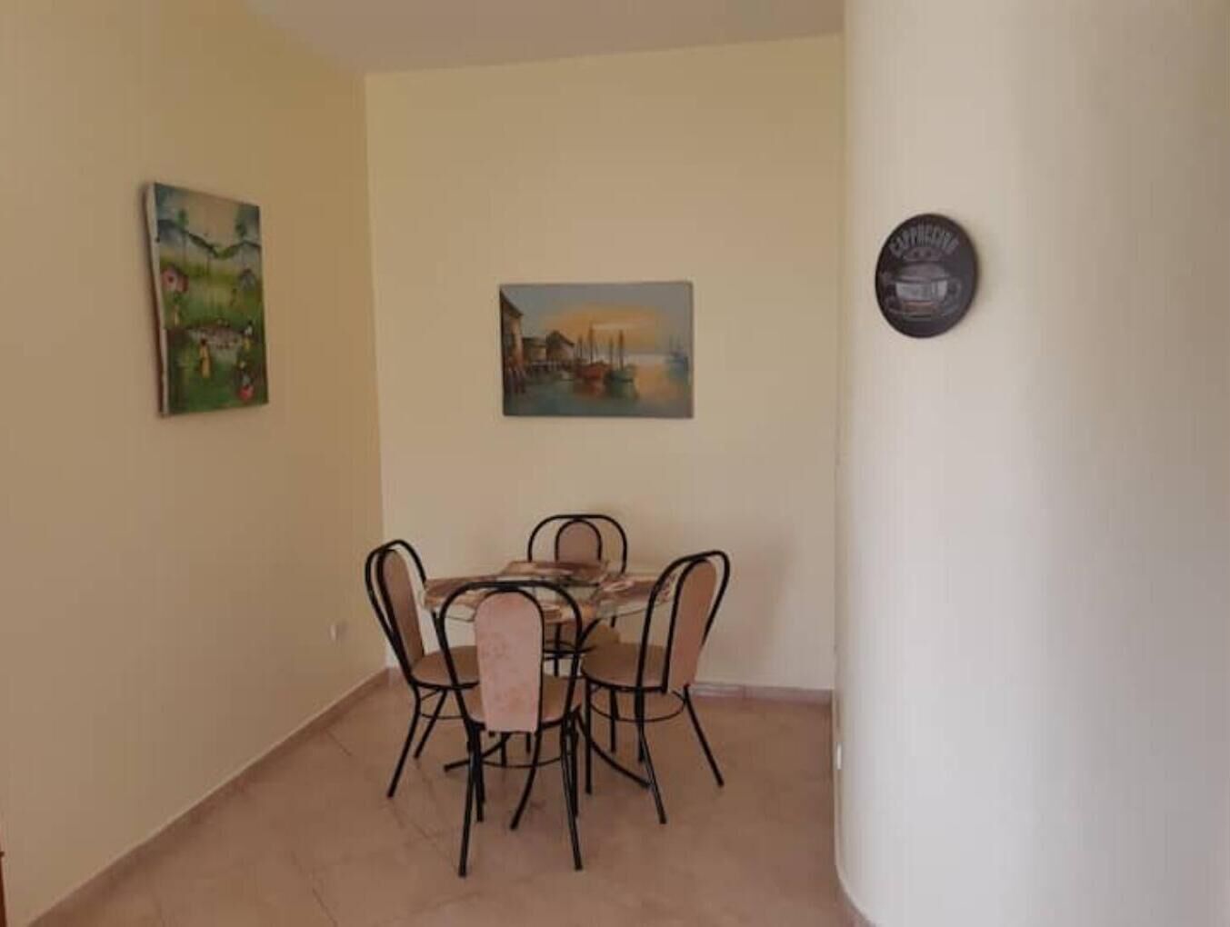 Un comedor con una mesa y cuatro sillas, un cuadro en la pared y una placa.