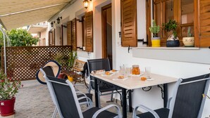 Un patio al aire libre con una mesa lista para comer, rodeado de sillas.