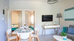 Una sala de estar moderna con comedor, un sofá, un televisor y una planta en maceta.