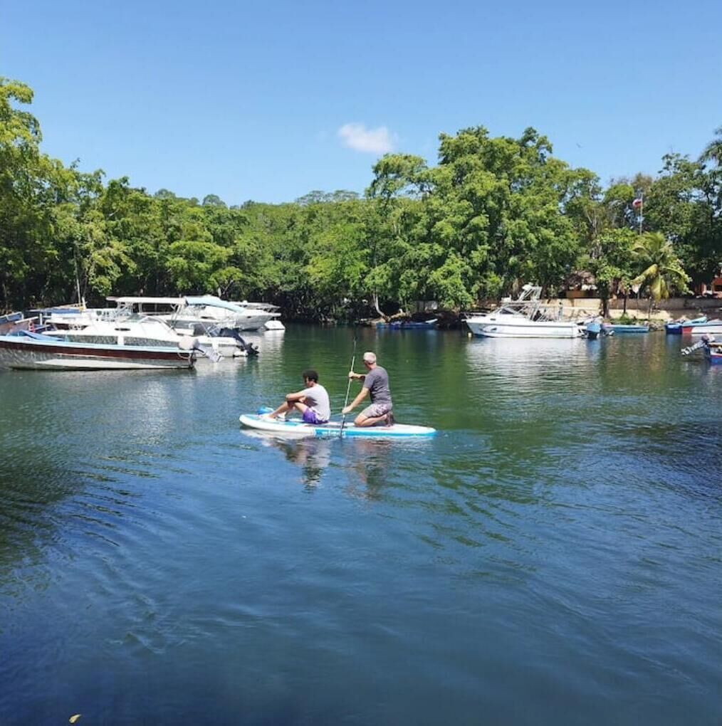 Un río tranquilo con barcos y gente haciendo paddleboard.