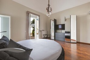 Een slaapkamer met een groot bed, een dressoir, een televisie en een spiegel.