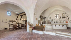 A rustic interior with arched ceilings, a dining area with wooden furniture, and a central seating area with a sofa.