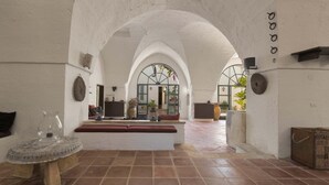 An interior with arched ceilings, a bench, a table, and a view through a window.