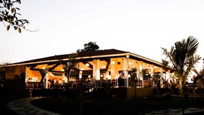 A large building with a covered outdoor area, possibly a restaurant or event space, with a stone pathway leading to it.