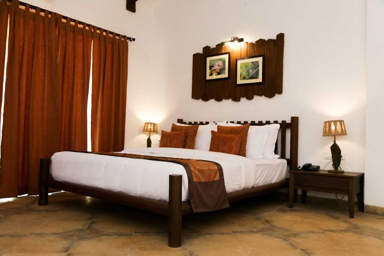Una cama bien hecha con cabecera de madera, dos lámparas de noche y una mesita de noche con lámpara.