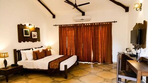 A bedroom with a bed, a desk, a chair, a ceiling fan, and curtains.