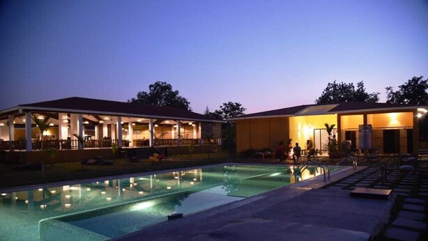A pool area with a covered seating area and a building with multiple windows.