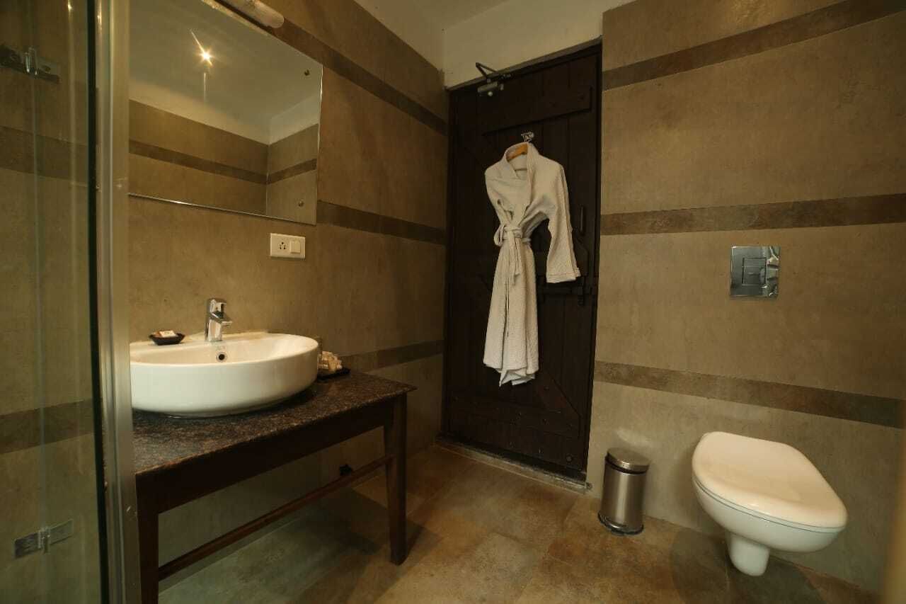 A bathroom with a sink, mirror, robe hanging, and toilet.