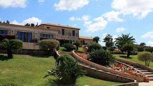 A building with a garden featuring a curved pathway and various plants. - Villaggio Club Dolomiti Sul Mare (Briatico)