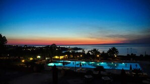 A resort with a large pool area, palm trees, and a sunset view. - Villaggio Club Dolomiti Sul Mare (Briatico)