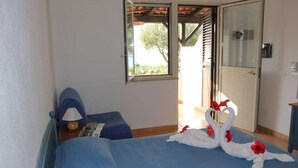 A bedroom with a bed, a nightstand, a lamp, and a window. - Villaggio Club Dolomiti Sul Mare (Briatico)