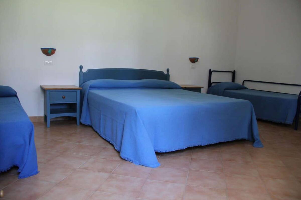 A bedroom with a single bed, a nightstand, and a small table.