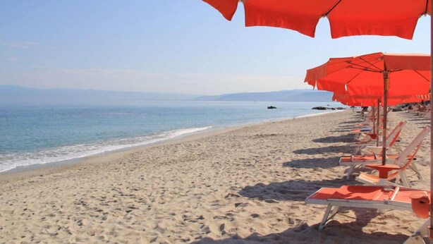 A beach with rows of orange umbrellas and beach chairs. - Villaggio Club Dolomiti Sul Mare (Briatico)