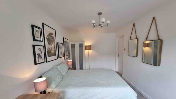 Une chambre à coucher comprenant un lit, des tables de chevet, une armoire et des œuvres d’art accrochées au mur.