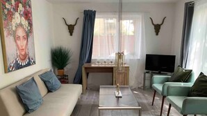 Un salon comprenant un canapé, une table basse, un téléviseur et un coin repas avec une table et des chaises.