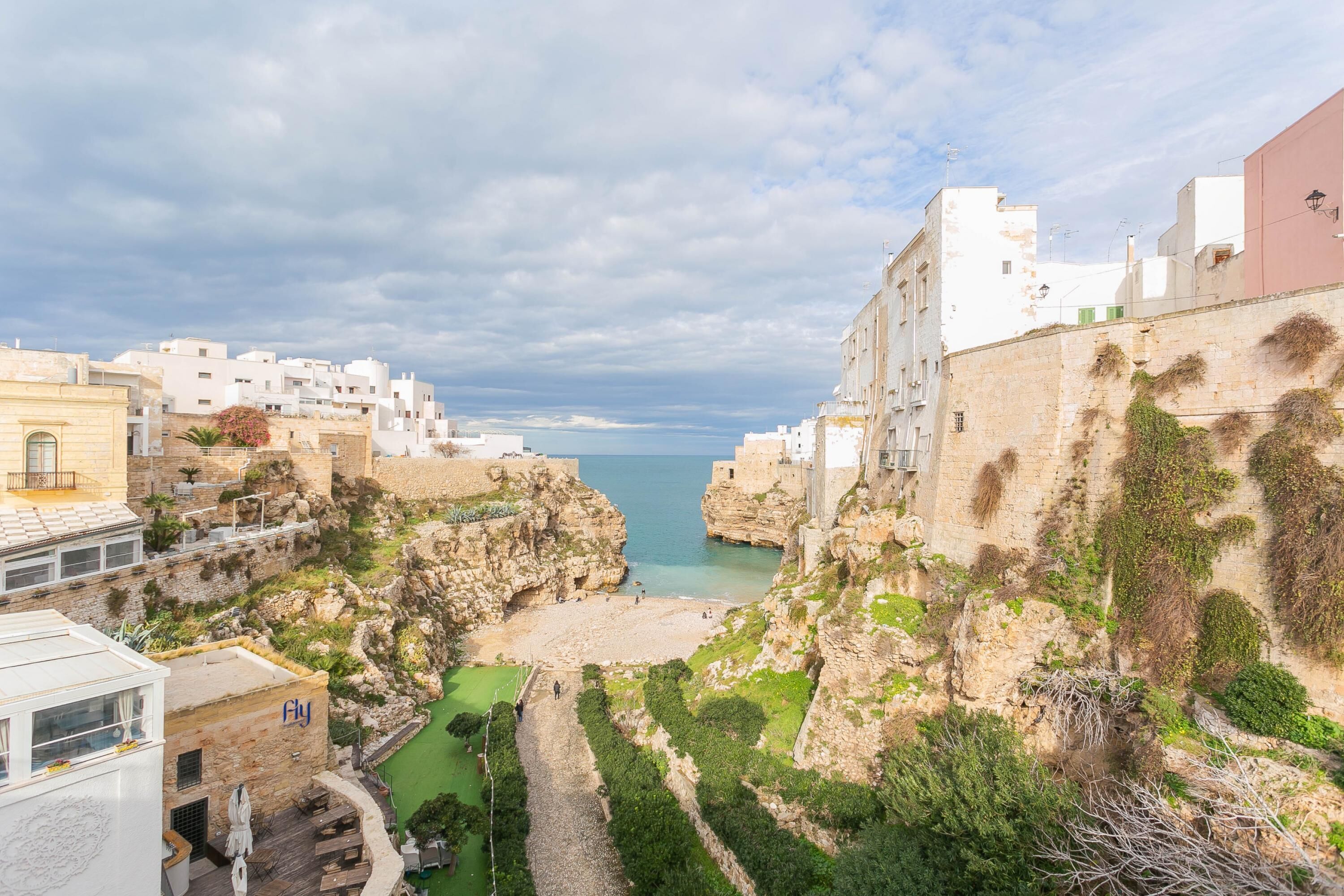A coastal town with buildings overlooking a rocky beach and the sea.