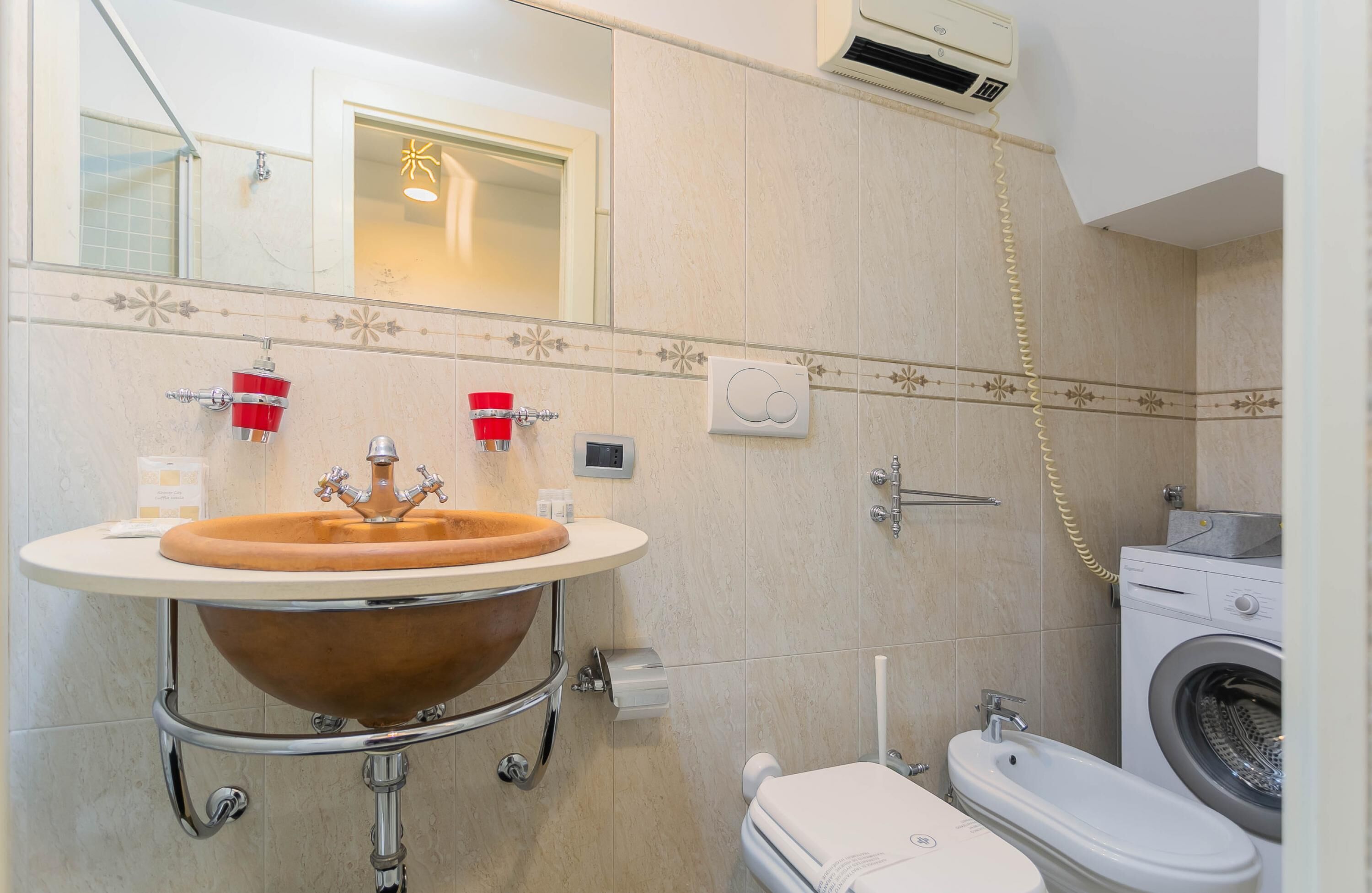 Un baño con un lavamanos grande, inodoro, lavadora y ducha.